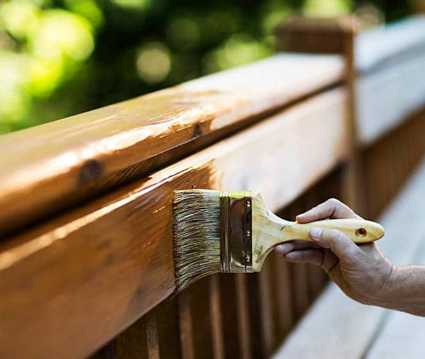 Homme qui applique du vernis sur du bois pour l'entretenir et le protéger