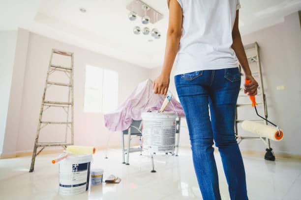 Jeune femme qui tient un pot de peinture pour rénover sa maison