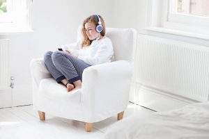 Femme assise dans un fauteuil blanc avec un chauffage électrique derrière elle