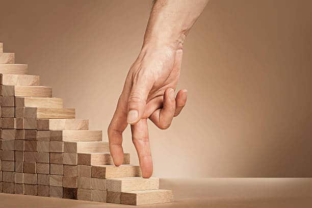 Main jouant sur une pile de batonnets en bois en forme d'escalier