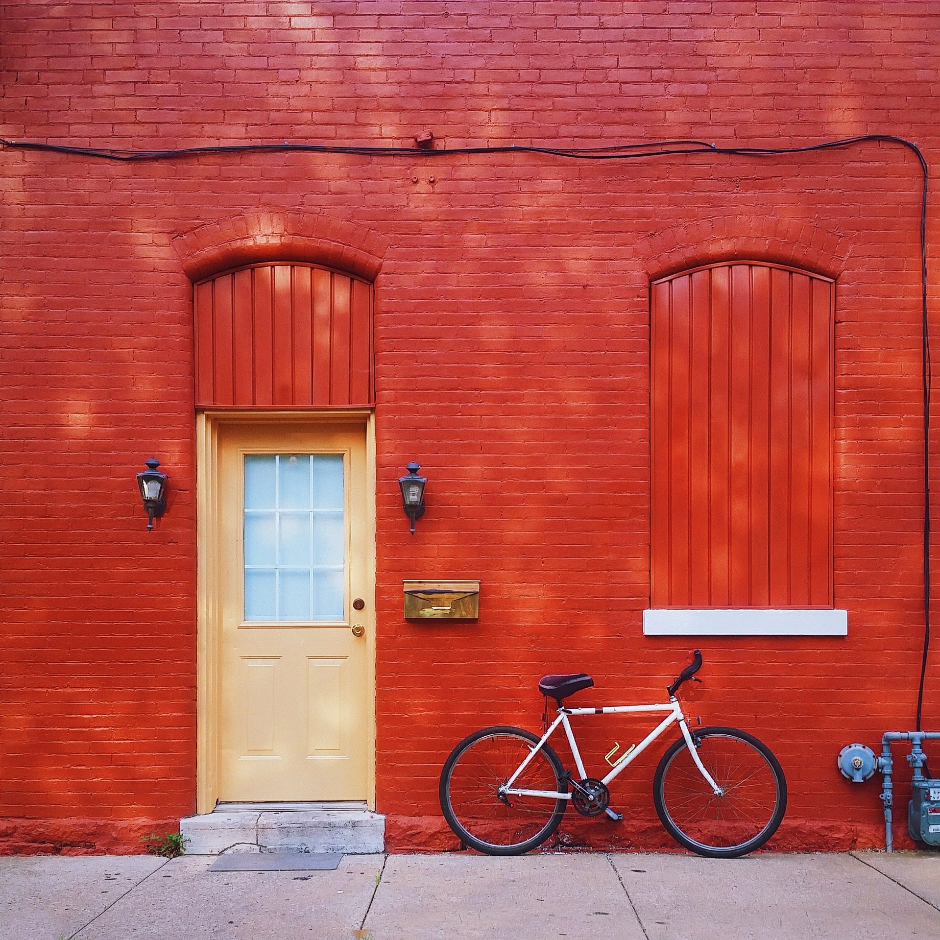 Porte d'entrée rue maison rouge avec vélo posé devant