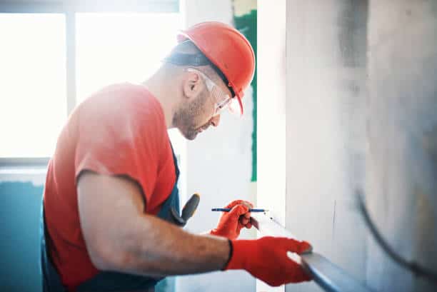 Ouvrier qui prend les mesures d'un mur en travaux