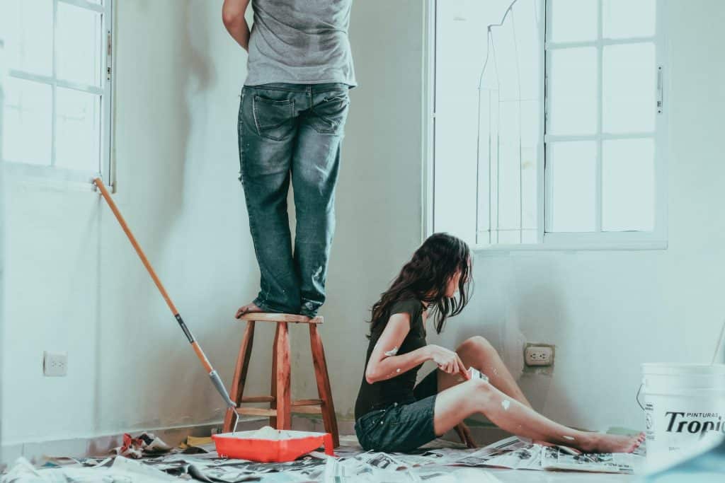 couple qui ponce un mur avant peinture
